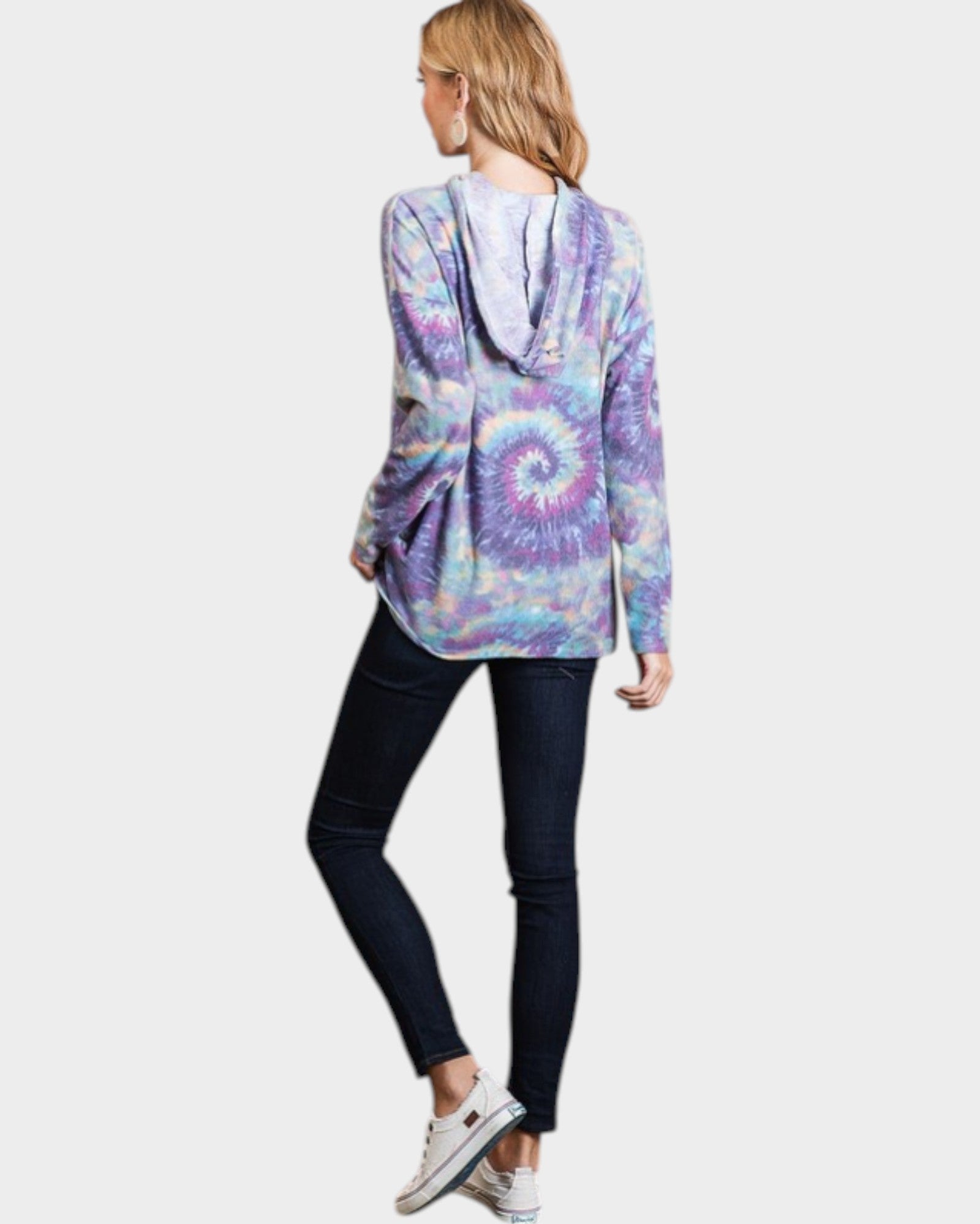 Person wearing a tie-dye hoodie and dark jeans on a white background