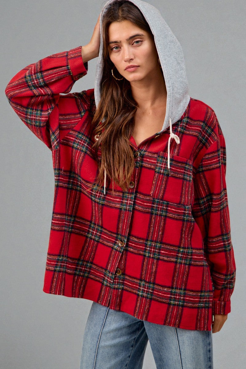 Person wearing a red plaid shirt with a gray hood against a gray background