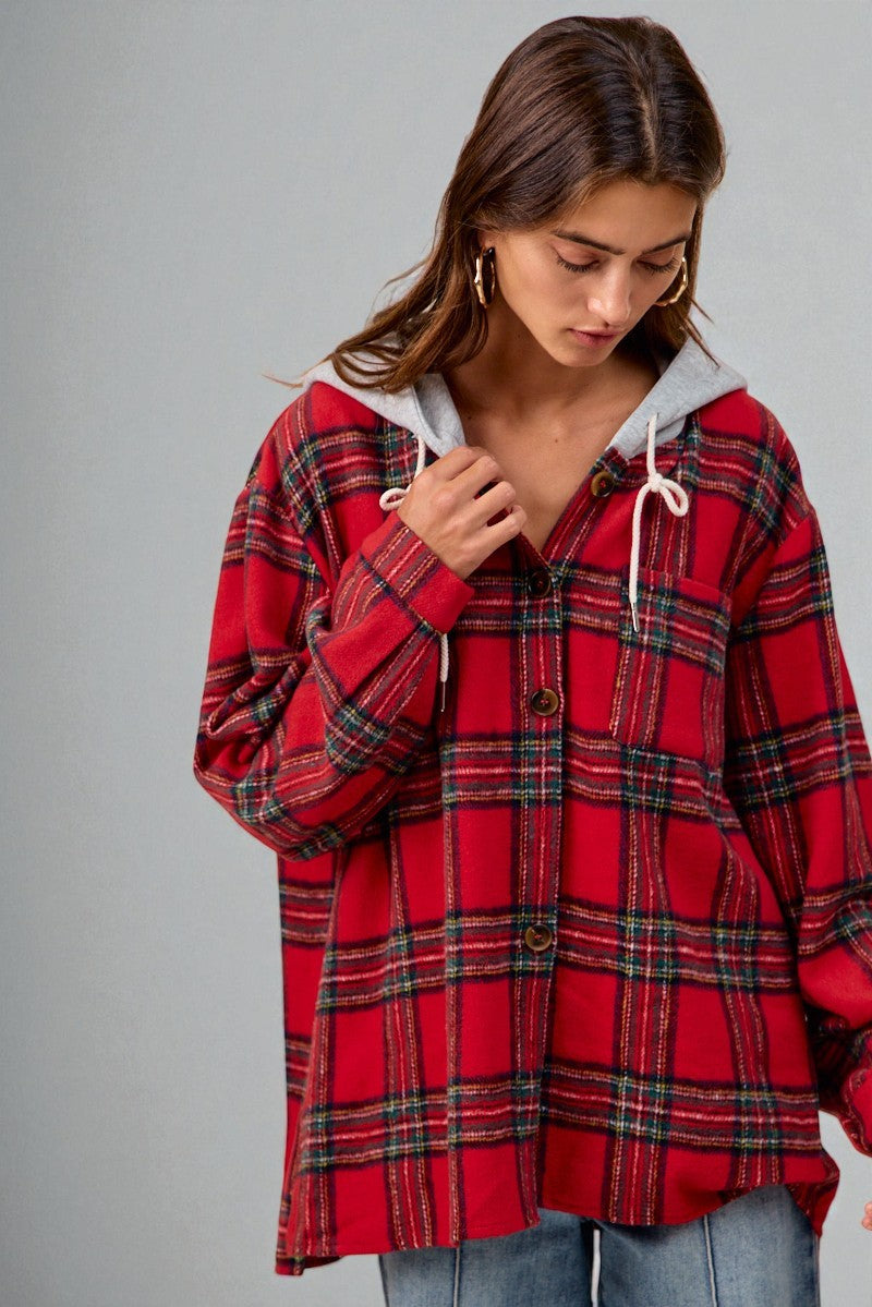 Person wearing a red plaid shirt with a gray hood against a gray background