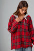 Person wearing a red plaid shirt with a gray hood against a gray background