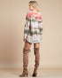 Person wearing a tie-dye sweater and brown knee-high boots on a beige background