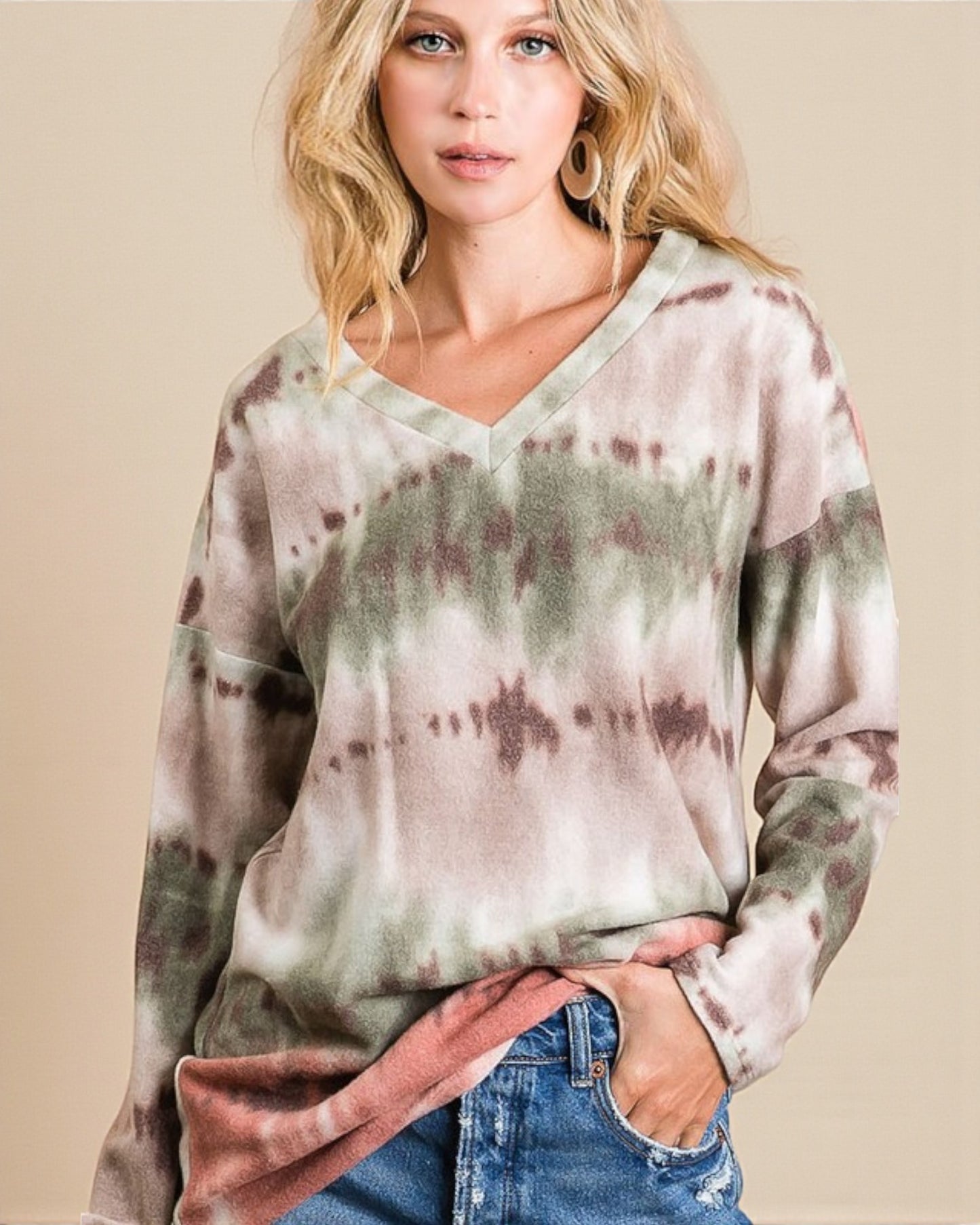 Woman wearing a tie-dye long-sleeve shirt against a beige background