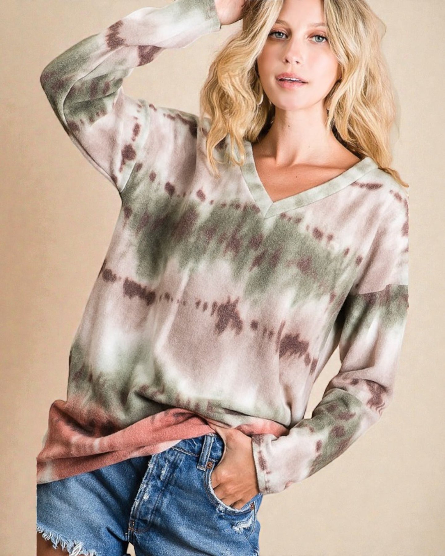 Woman wearing a tie-dye long-sleeve shirt and jeans against a beige background