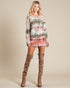 Woman wearing a tie-dye dress and brown knee-high boots on a beige background