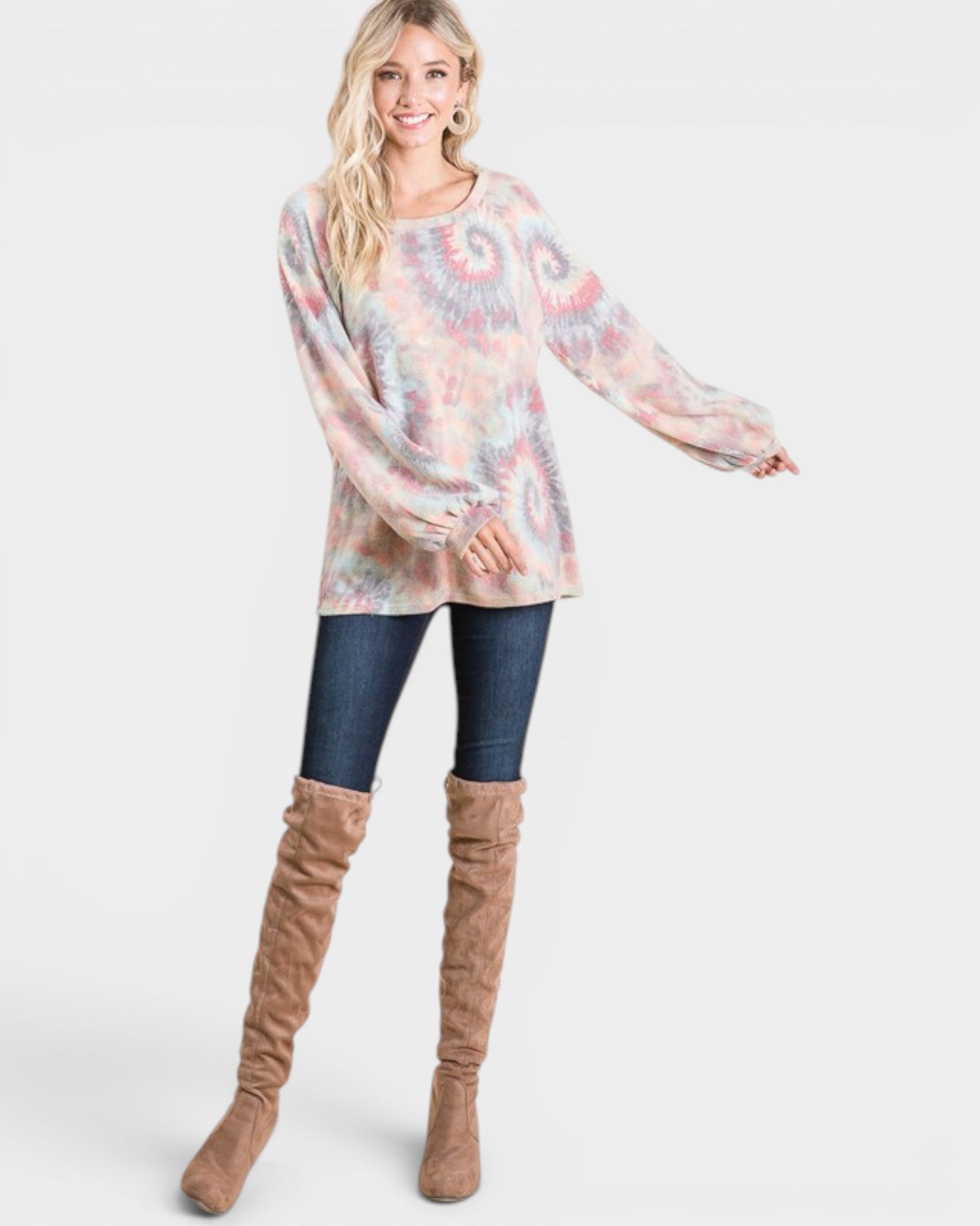 Woman wearing a tie-dye sweater and brown knee-high boots on a white background