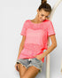 Woman wearing a pink t-shirt and denim shorts on a light gray background