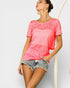 Woman wearing a pink ombre top and denim shorts on a plain background