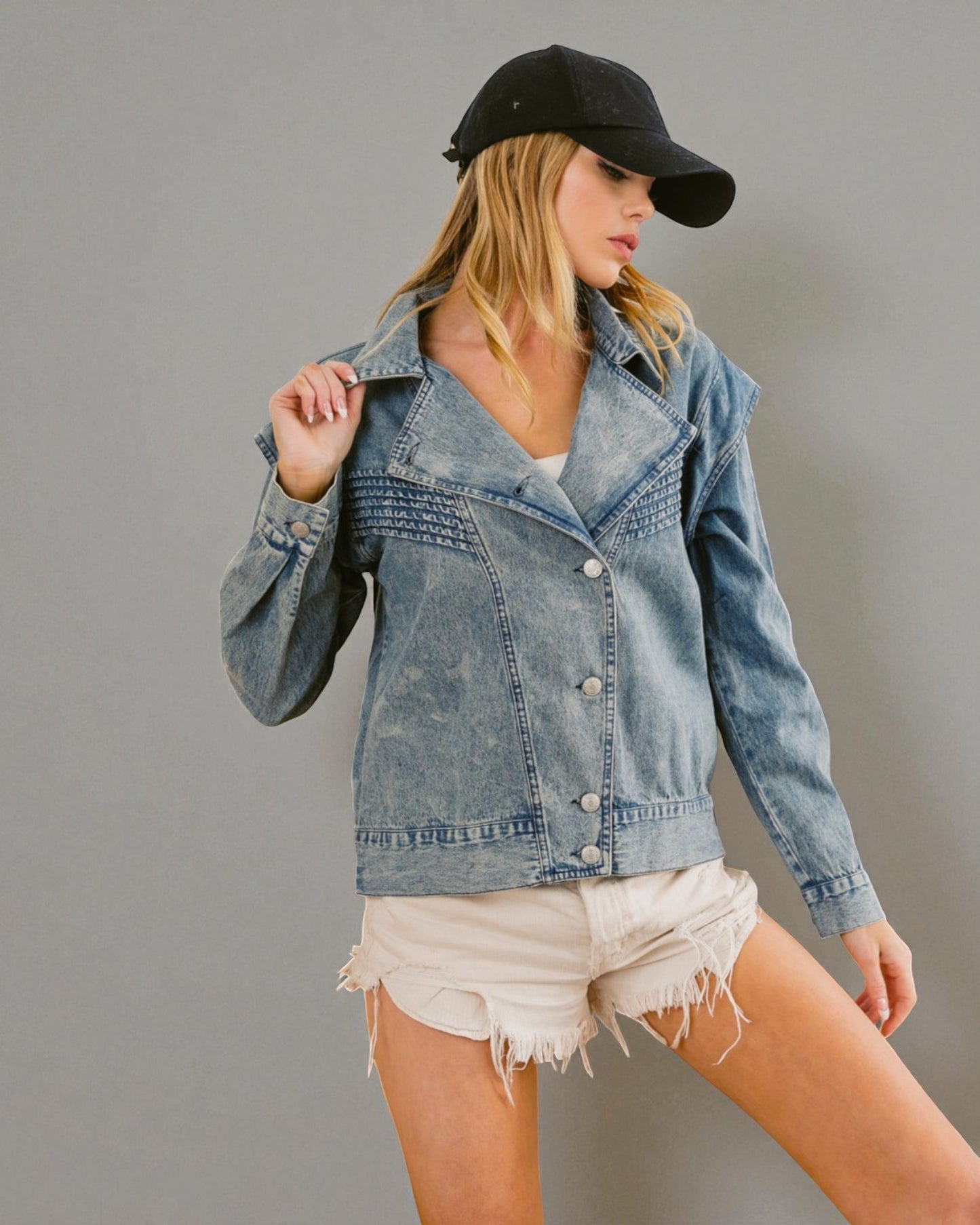 Woman wearing a denim jacket and black cap on a gray background