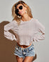 Woman wearing a light pink textured long-sleeve top and denim shorts against a plain background