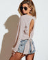 Woman wearing a light-colored sleeveless top and denim shorts against a white background