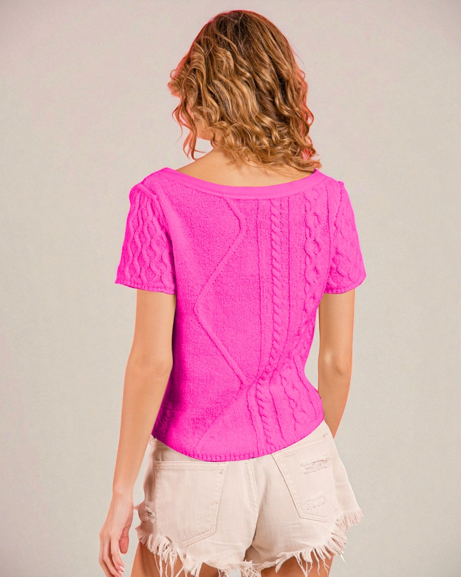 Person wearing a bright pink top with a textured pattern on a plain background