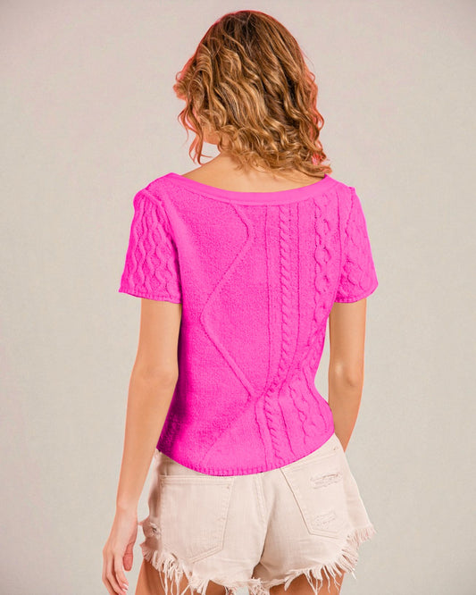 Person wearing a bright pink top with a textured pattern on a plain background