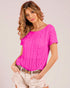 Woman wearing a bright pink textured top against a plain background