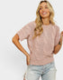 Woman wearing a pink cable knit sweater and light blue jeans on a white background