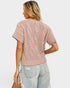 Woman wearing a pink knitted sweater and light blue jeans on a white background