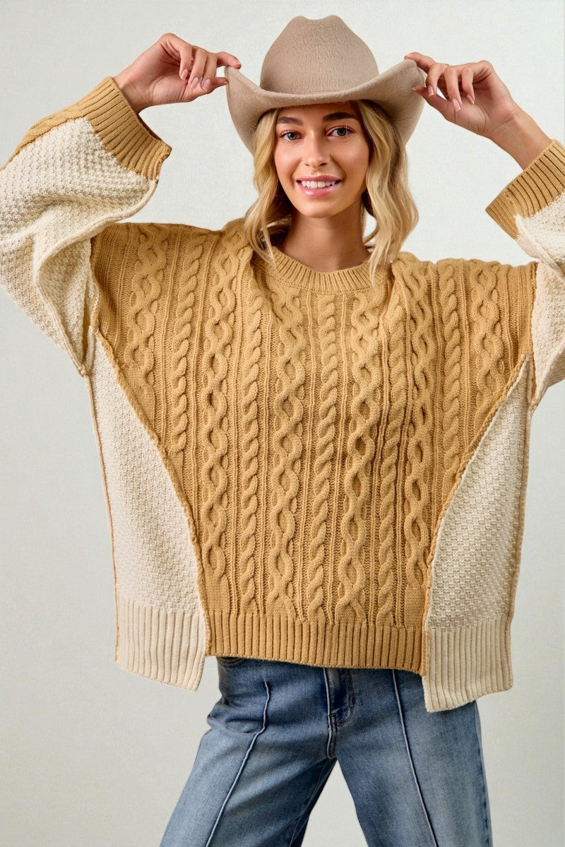 Person wearing a mustard yellow sweater with beige sleeves and a beige cowboy hat.
