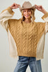 Person wearing a mustard yellow sweater with beige sleeves and a beige cowboy hat.