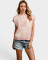 Woman wearing a pink and white checkered sleeveless top with denim shorts on a white background