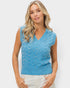 Woman wearing a blue knitted vest with pearl embellishments on a white background