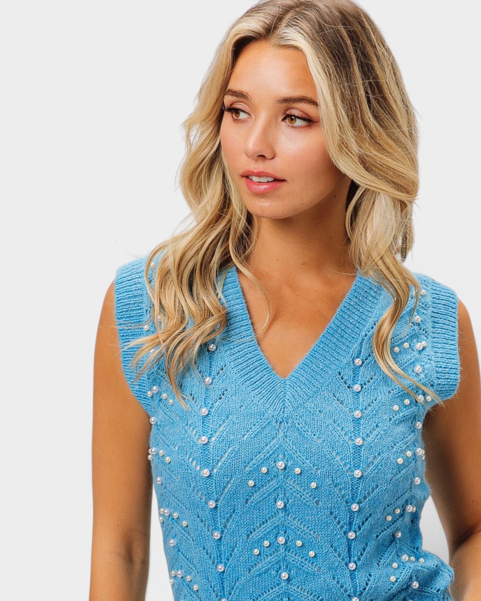 Woman wearing a blue beaded dress against a white background