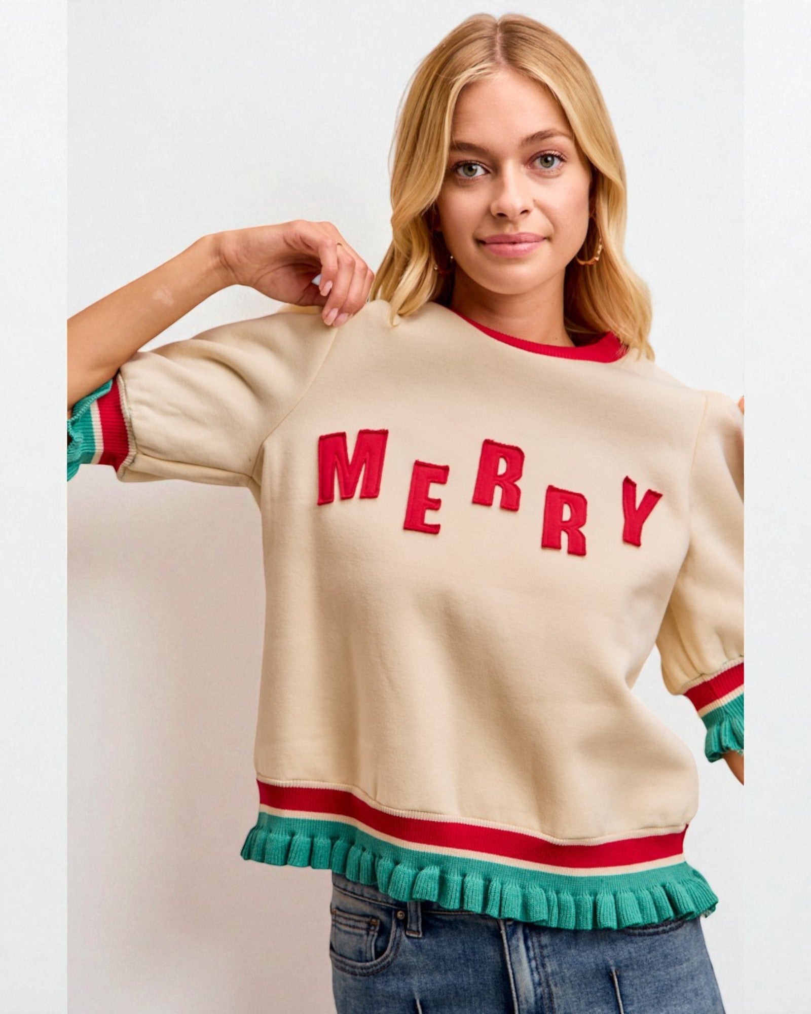 Woman wearing a cream sweater with 'MERRY' in red letters on a white background