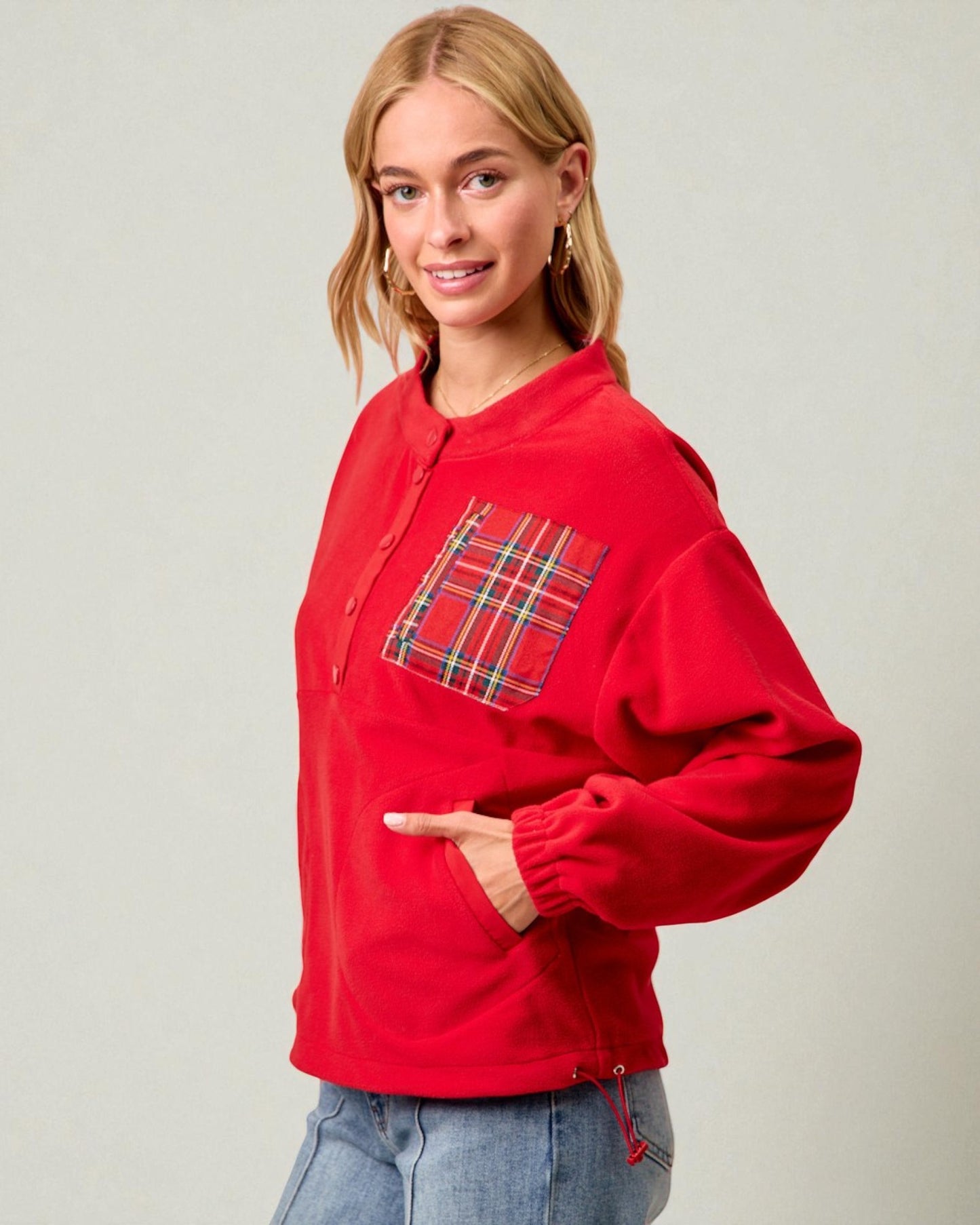 Person wearing a red jacket with a plaid pocket on a plain background