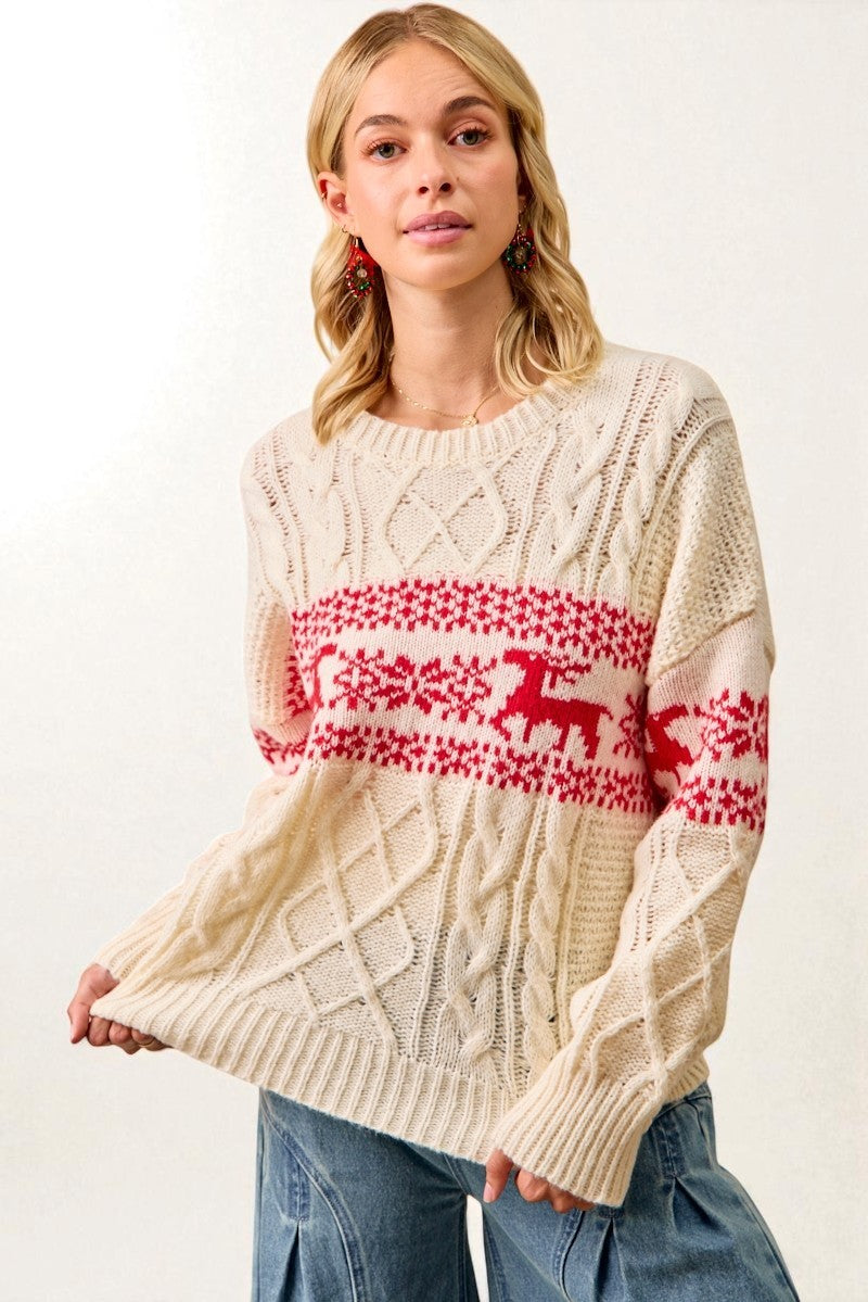 Woman wearing a cream sweater with red deer pattern on a white background