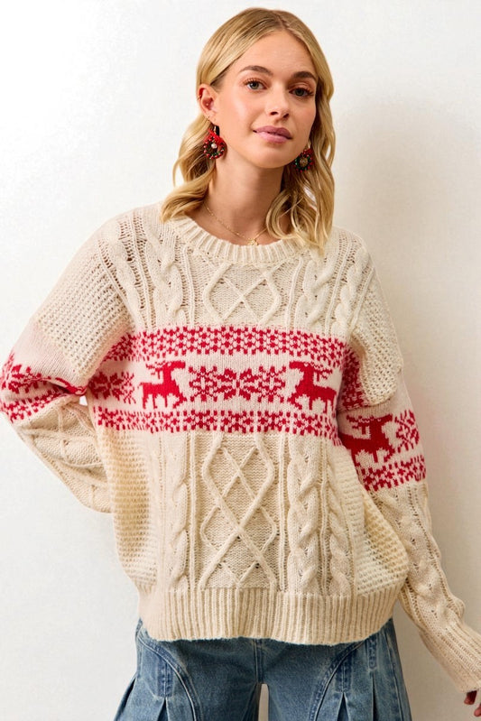 Woman wearing a cream sweater with red deer pattern against a white background