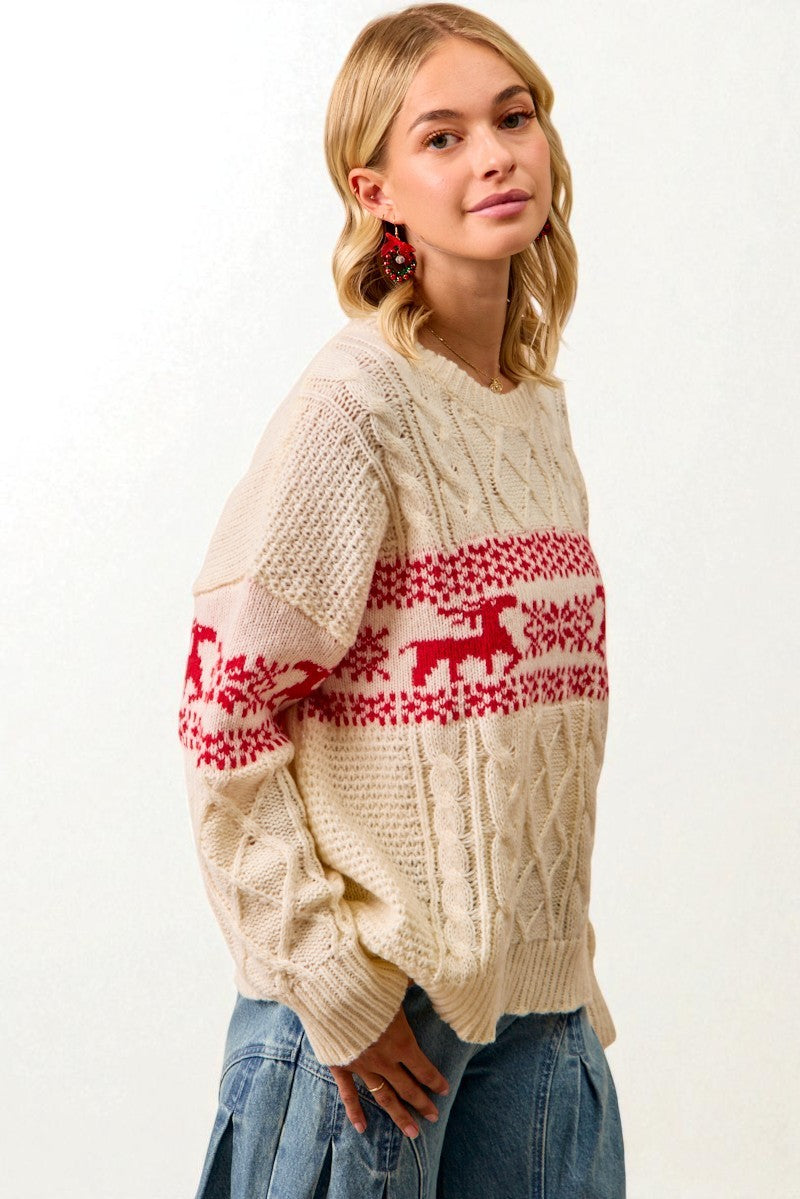 Woman wearing a cream sweater with red reindeer pattern on a white background
