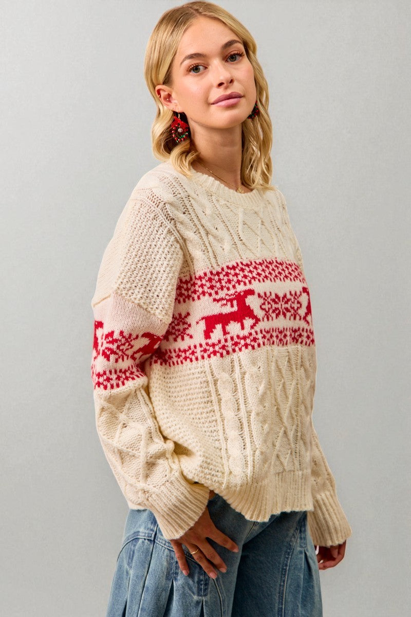 Woman wearing a cream sweater with red and white pattern against a gray background