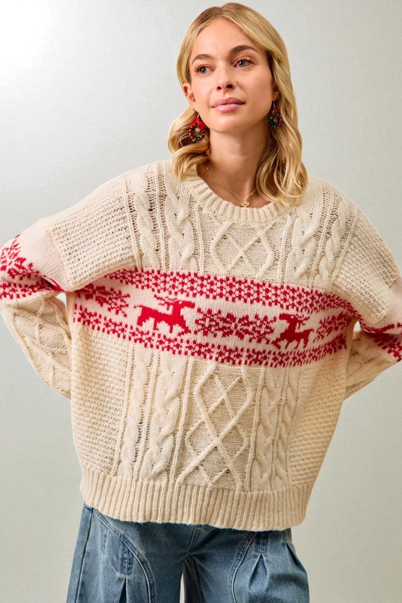 Woman wearing a cream sweater with red reindeer pattern against a plain background