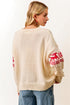 Woman wearing a cream sweater with red reindeer patterns on sleeves against a white background