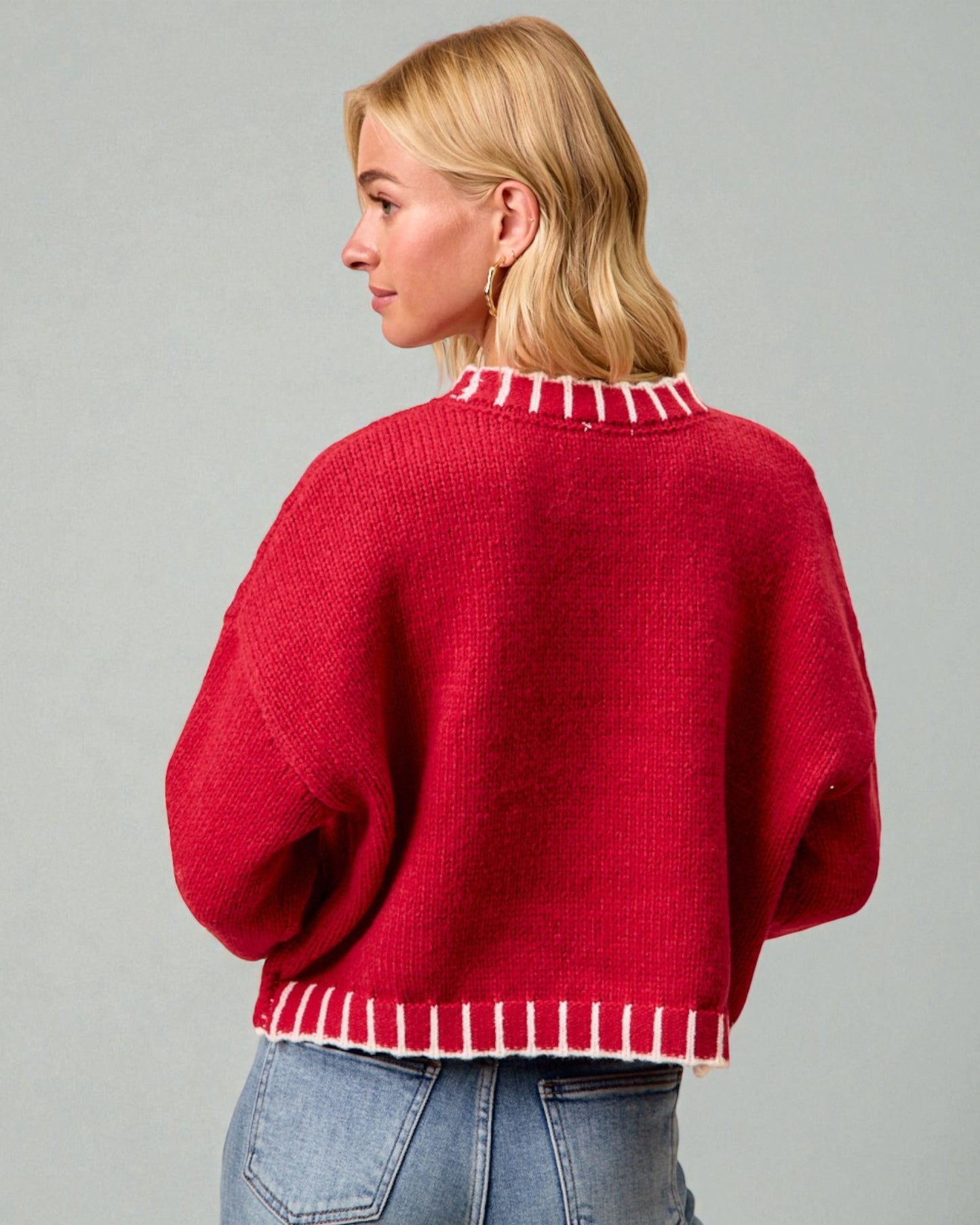 Woman wearing a red sweater with white trim on a gray background
