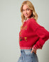 Woman wearing a red sweater with colorful text on a plain background