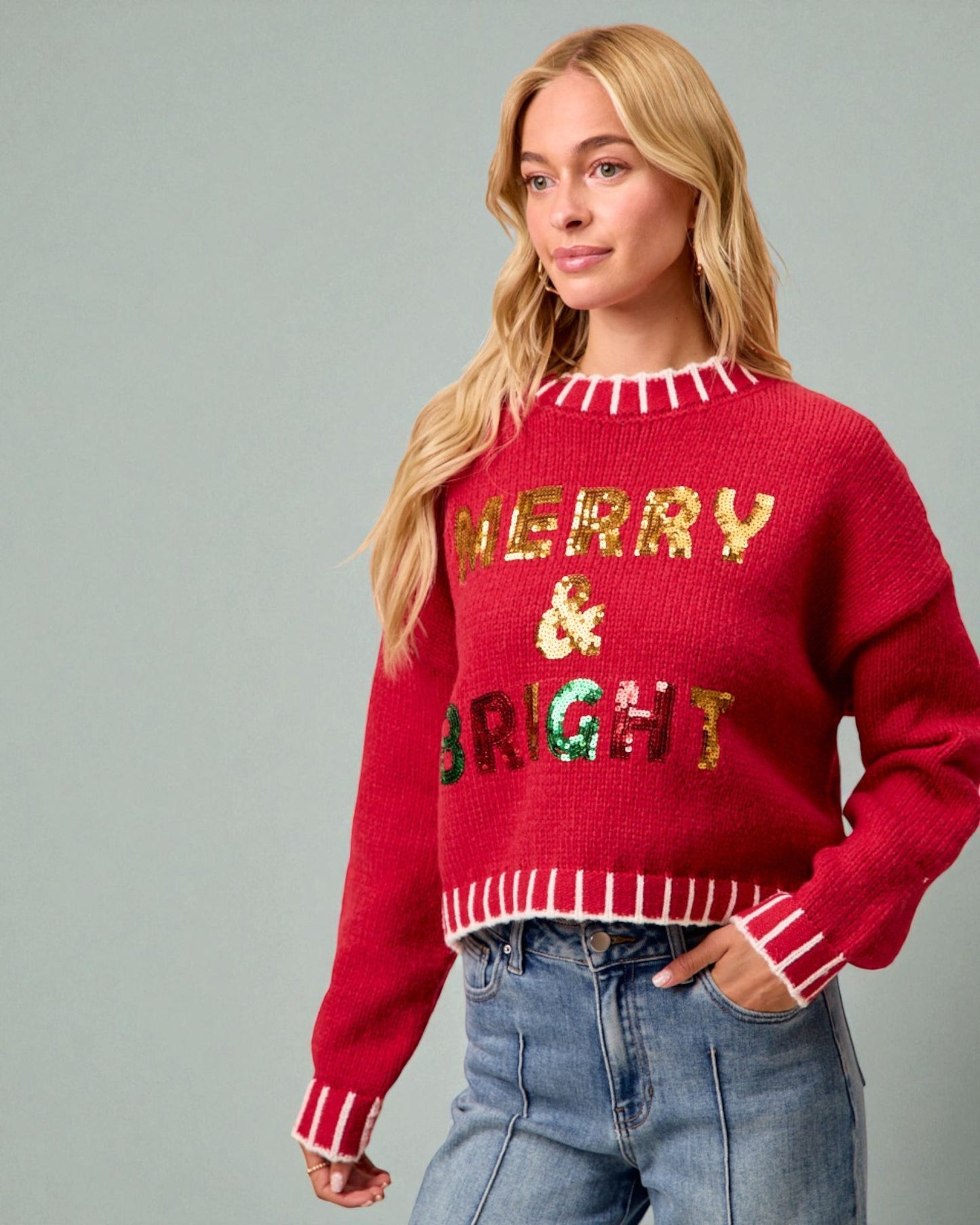 Woman wearing a red sweater with 'Merry & Bright' text on a gray background