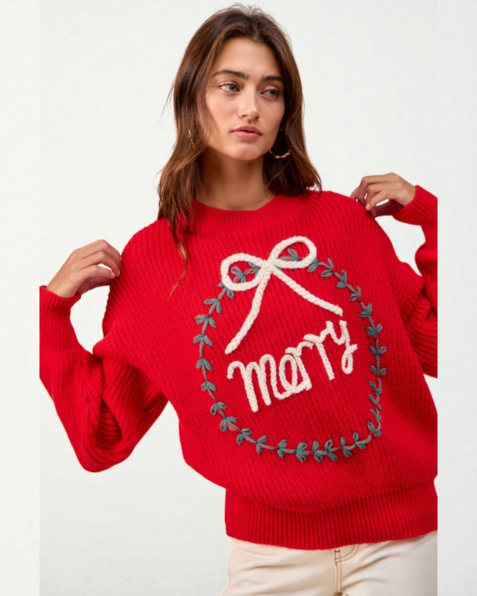 Person wearing a red sweater with 'Merry' and a bow design on a white background