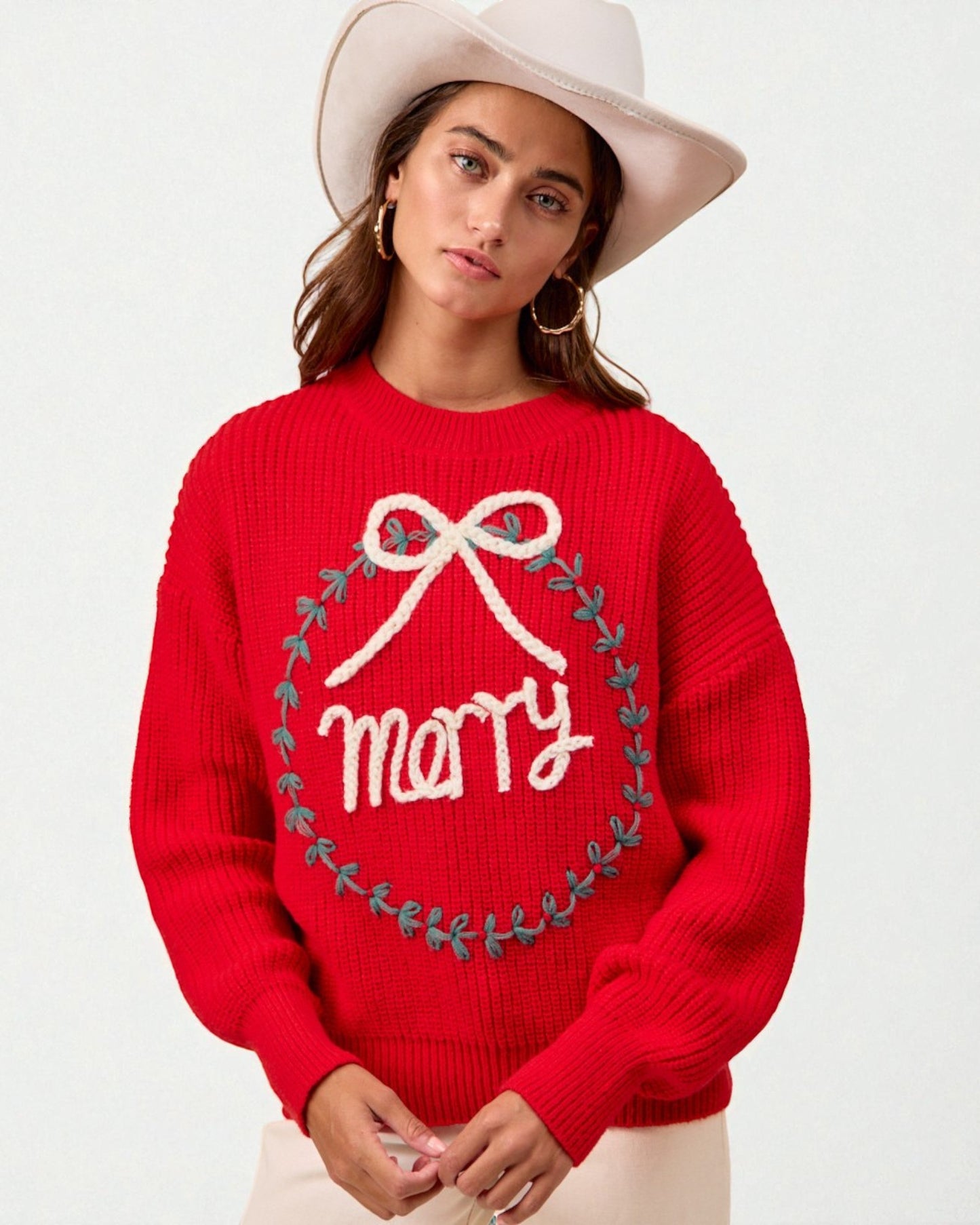 Person wearing a red sweater with 'merry' and a bow design on a white background
