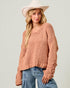 Woman wearing a pink knit sweater and wide-brimmed hat on a plain background
