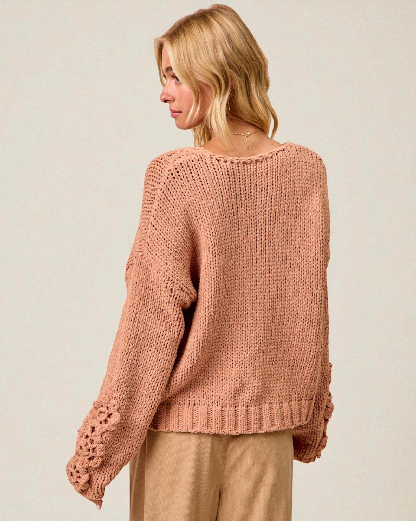 Woman wearing a pink knitted sweater on a plain background
