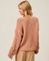 Woman wearing a pink knitted sweater on a plain background