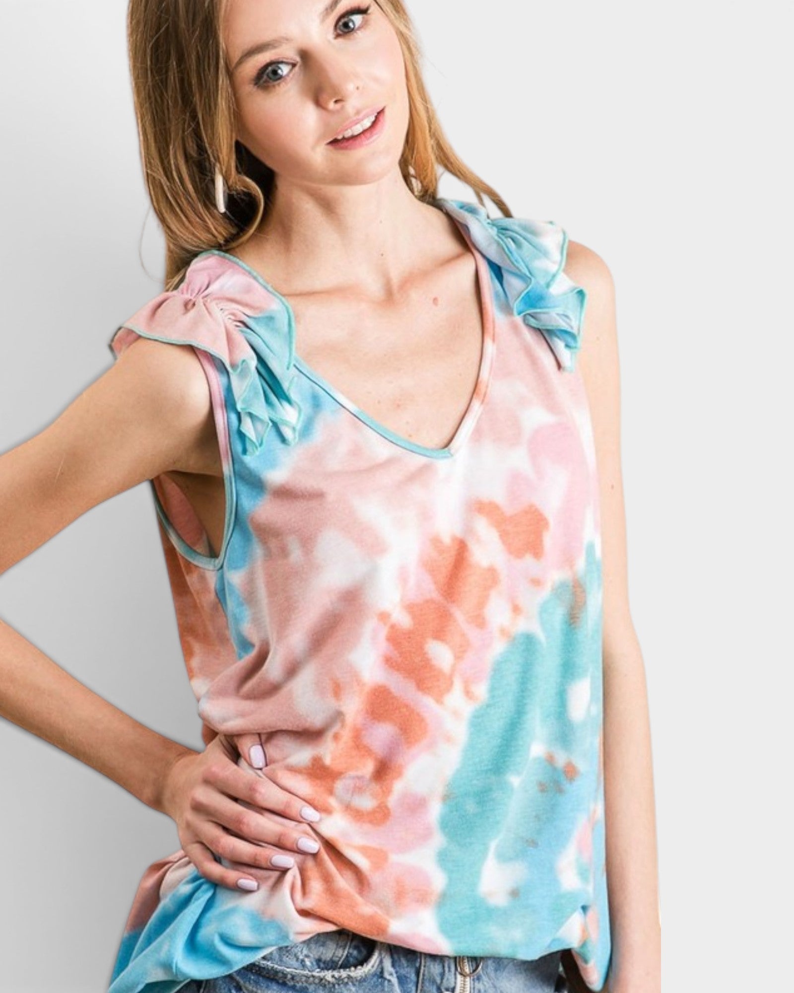 Woman wearing a colorful tie-dye top with ruffled sleeves on a plain background