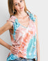 Woman wearing a colorful tie-dye top with ruffled sleeves on a plain background