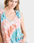 Woman wearing a tie-dye sleeveless top with ruffled shoulders on a white background