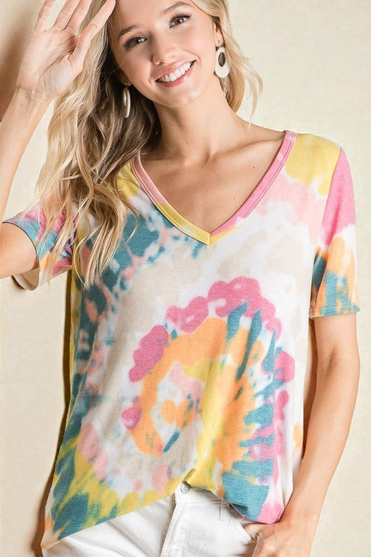 Woman wearing a colorful tie-dye shirt with a plain background