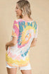 Woman wearing a colorful tie-dye shirt against a beige background