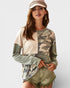 Woman wearing a camouflage and beige long-sleeve shirt with shorts on a white background