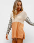 Woman wearing a two-tone sweater with leopard print sleeves on a white background