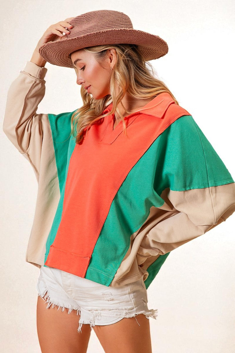 Woman wearing a colorful jacket with a hat on a plain background