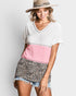 Woman wearing a color-blocked top with pink and leopard print shorts on a plain background