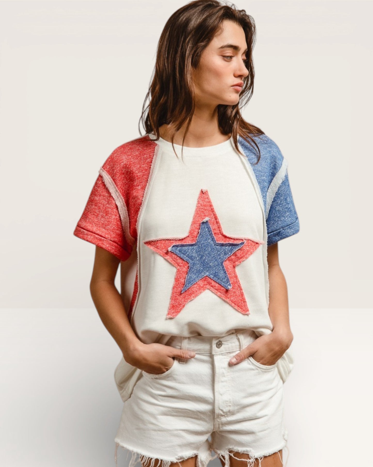 Woman wearing a white t-shirt with a red and blue star design on a plain background